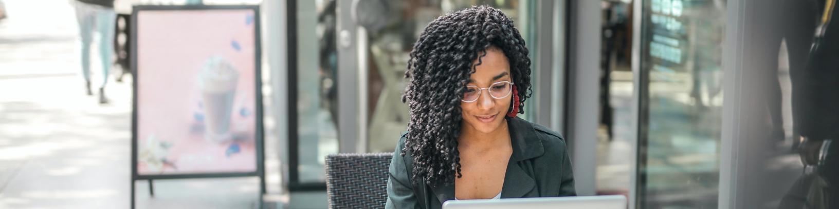 Uma mulher negra está sentada diante de seu laptop.
