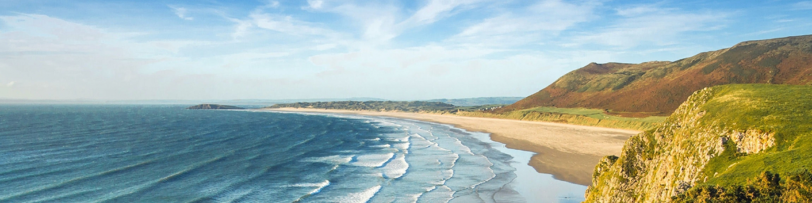 À esquerda, o mar. À direita, praia e montanhas.