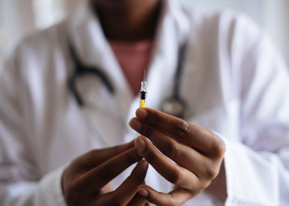 Uma injeção contendo líquido dentro está sendo mostrada para quem bateu a foto, por um médico ou enfermeiro
