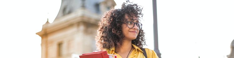 Mulher com cabelo enrolado olha para a direita, com uma igreja ao fundo.